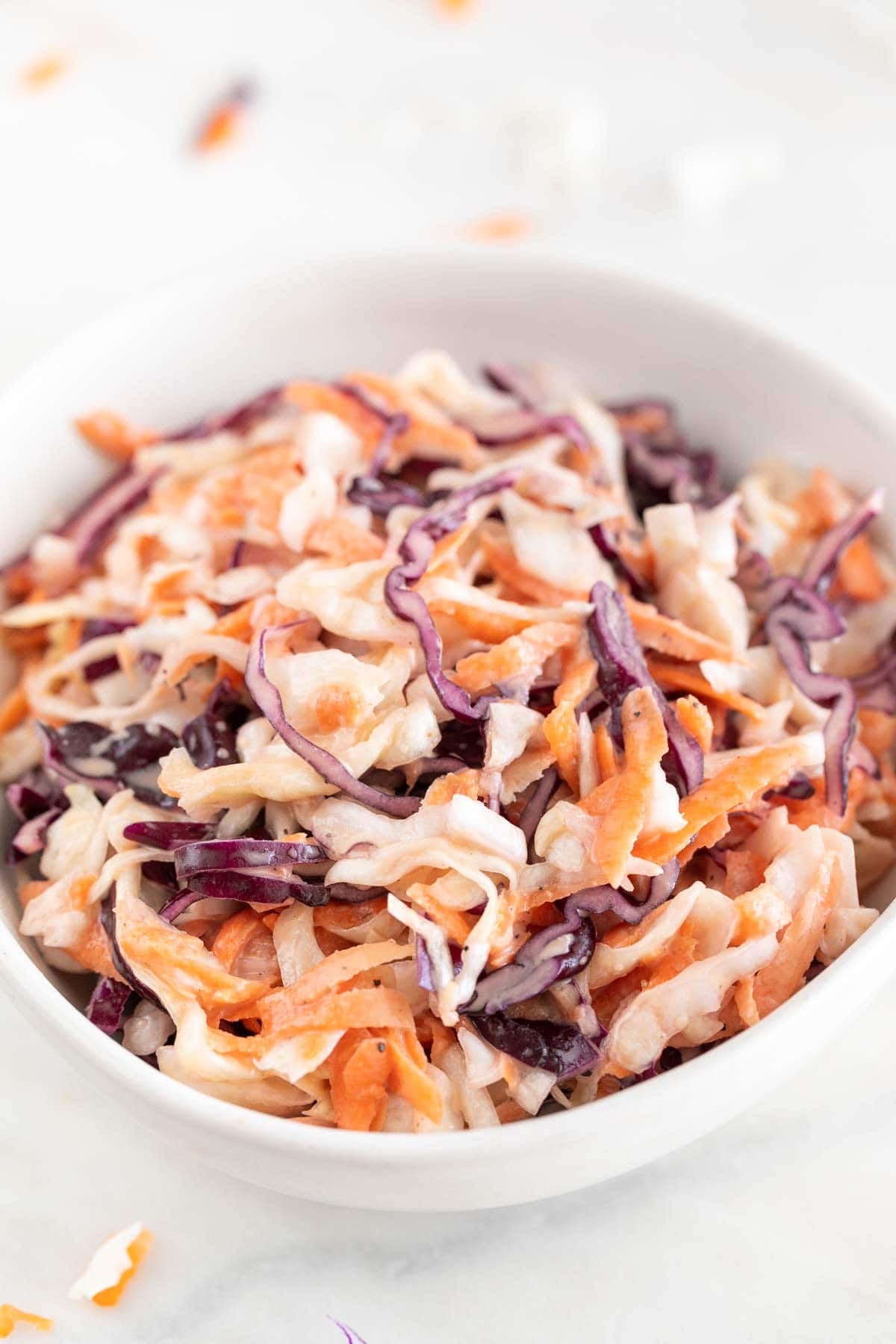 Vegan coleslaw served in a bowl on a marble surface