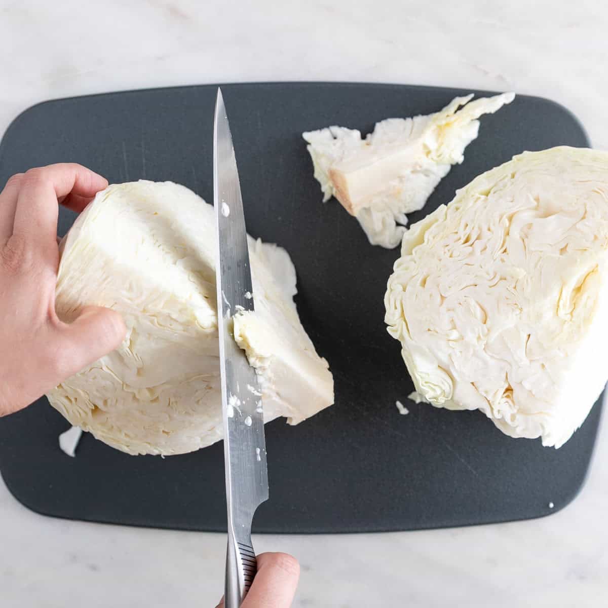 Removing the core from quartered cabbage on a cutting board