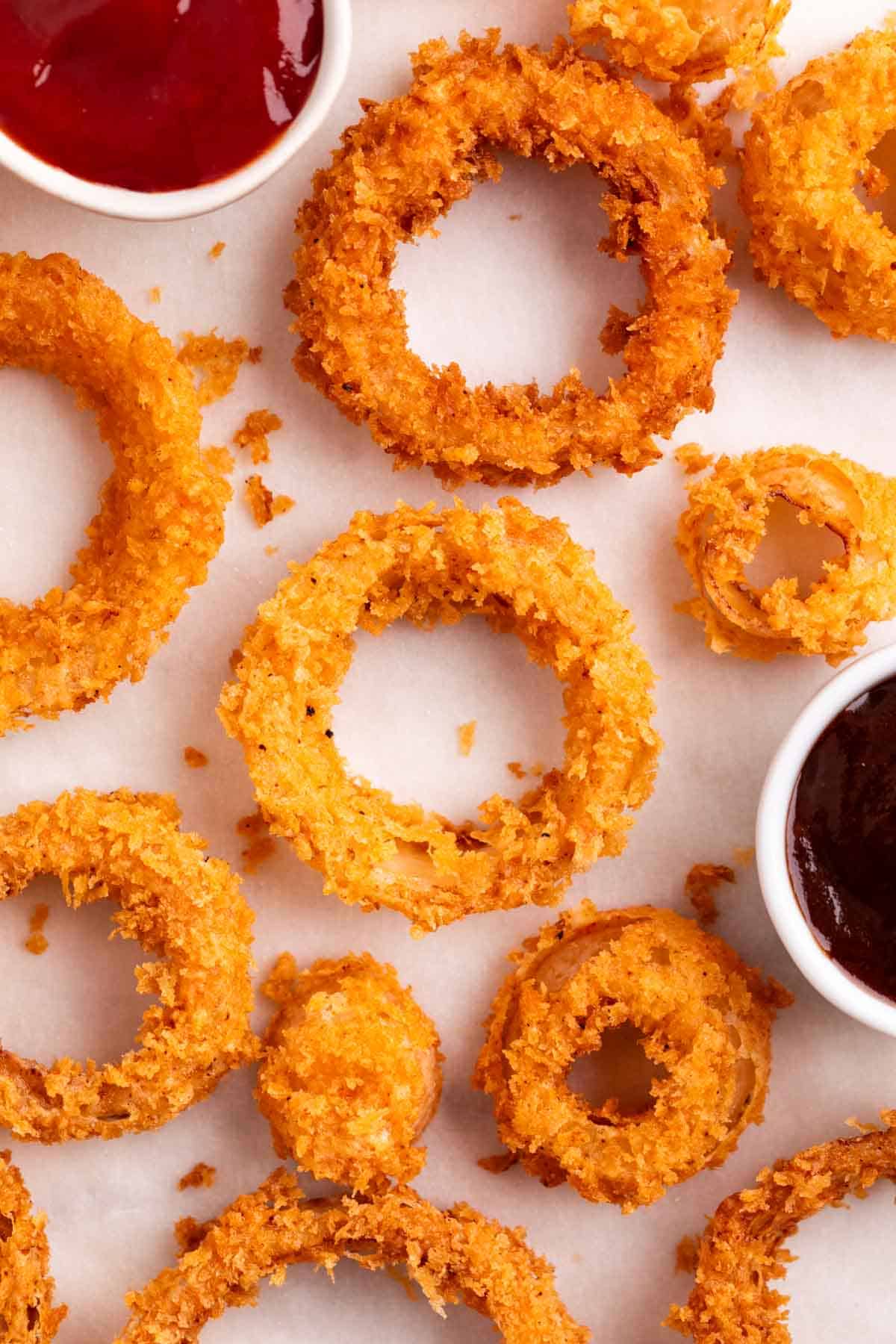 Homemade onion rings with small bowls of ketchup and barbecue sauce for dipping