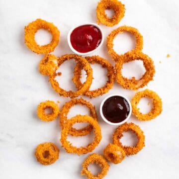 Crispy vegan onion rings served with barbecue sauce and ketchup on the side
