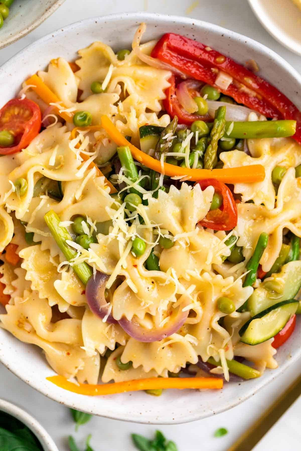 Close-up of vegan pasta primavera with asparagus, peas, and vegan cheese