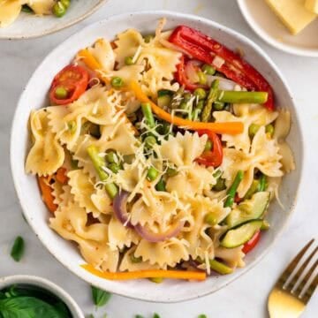 Homemade vegan pasta primavera topped with basil and grated vegan cheese