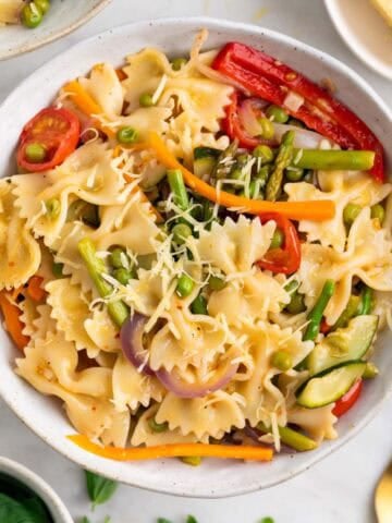 Homemade vegan pasta primavera topped with basil and grated vegan cheese