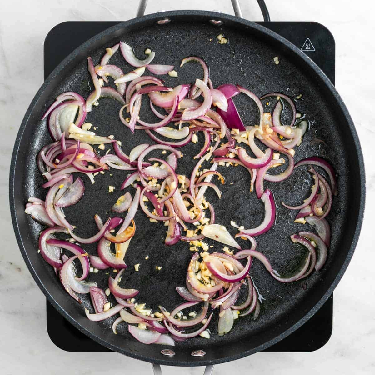 Red onion and minced garlic cooking in a large skillet
