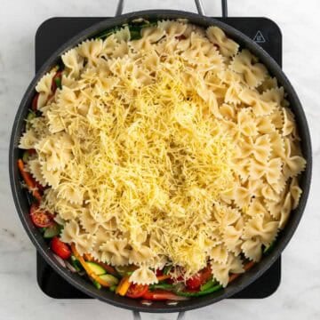 Cooked pasta, vegan cheese, lemon zest, and lemon juice added to the skillet