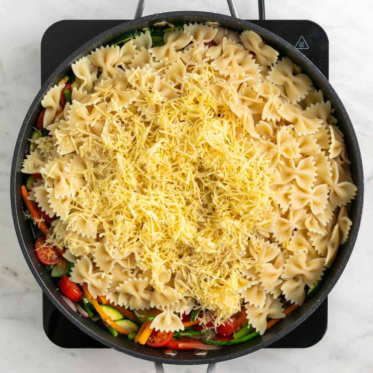 Cooked pasta, vegan cheese, lemon zest, and lemon juice added to the skillet