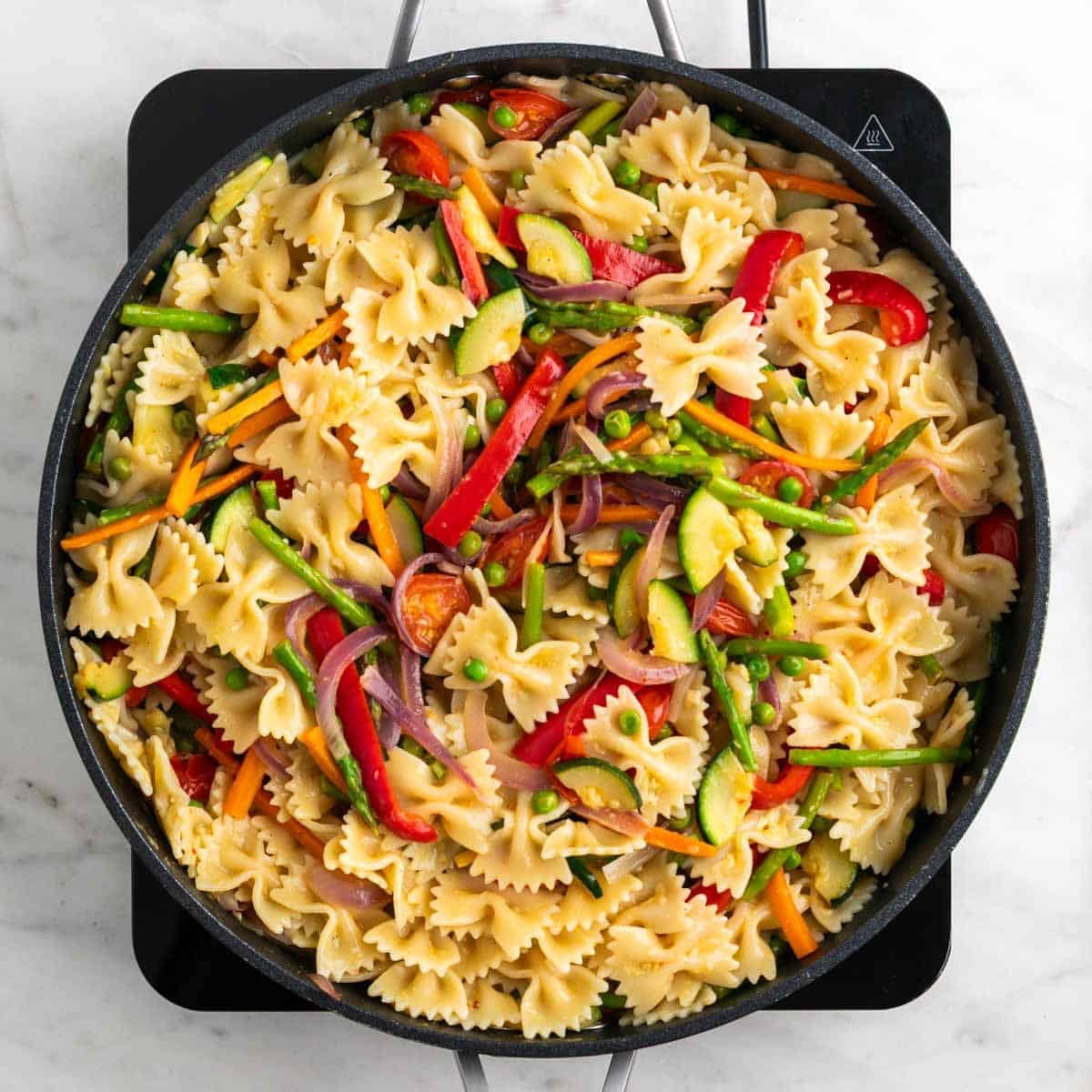 Vegan pasta primavera tossed in a skillet until glossy and creamy
