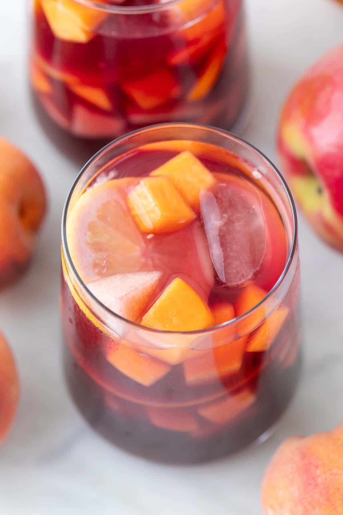 Two glasses of Spanish sangria with ice and fresh fruit around them