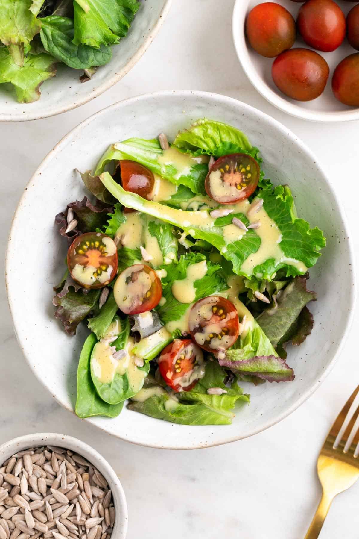 Bowl of salad topped with creamy vegan salad dressing