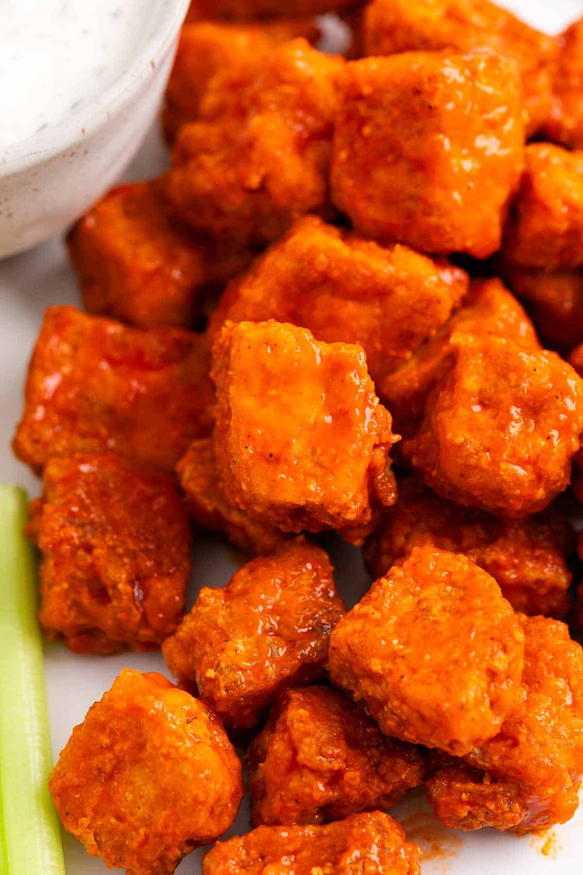 Plate of buffalo tofu bites with celery and vegan ranch dressing