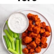 Buffalo tofu appetizer with celery sticks and a bowl of vegan ranch dressing