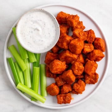 Buffalo tofu served on a plate with celery sticks and vegan ranch dressing