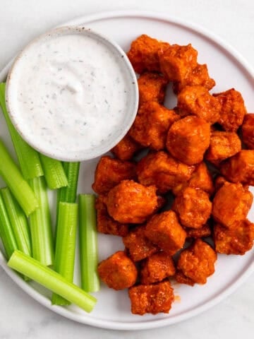 Buffalo tofu served on a plate with celery sticks and vegan ranch dressing