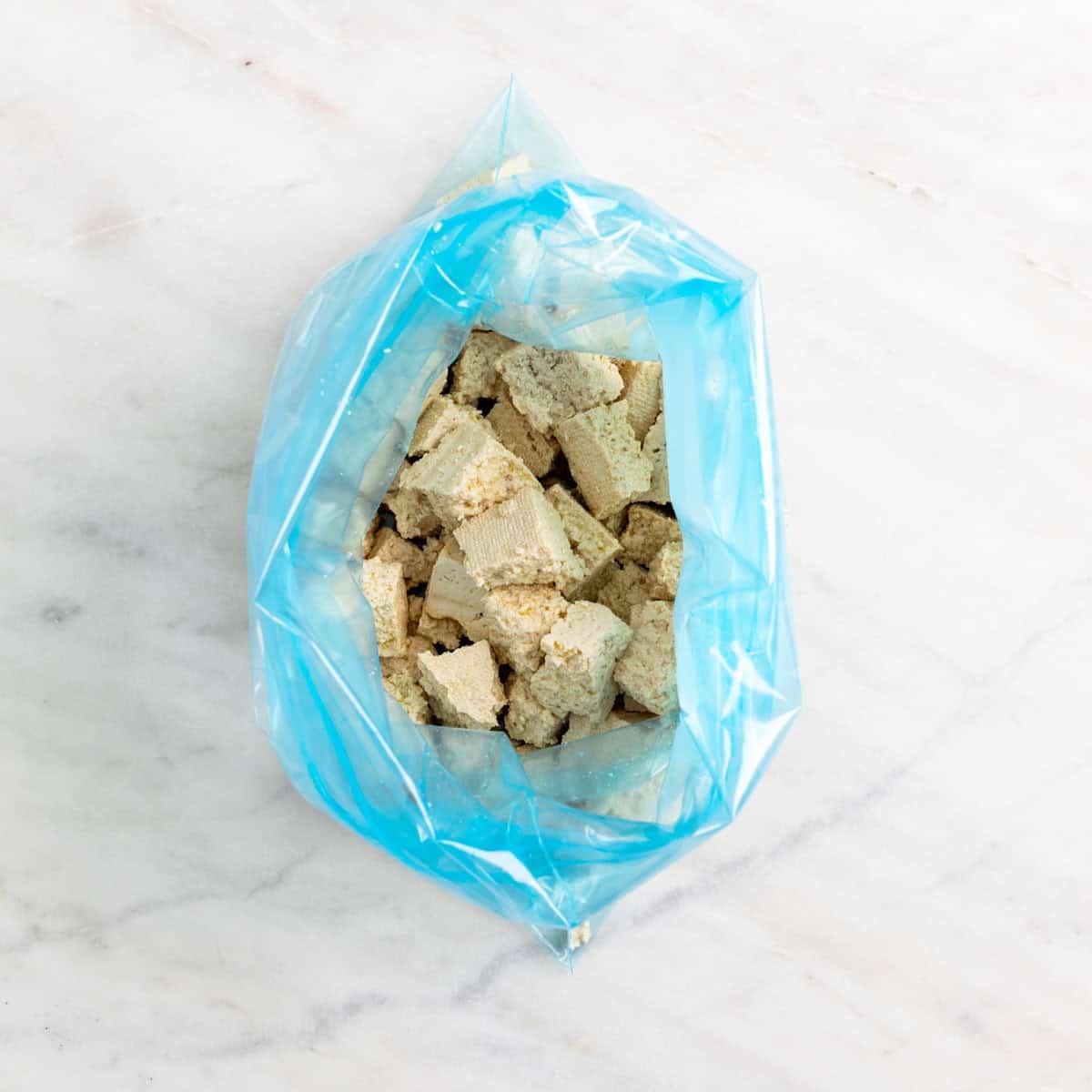 Tofu pieces tossed with olive oil in a freezer bag