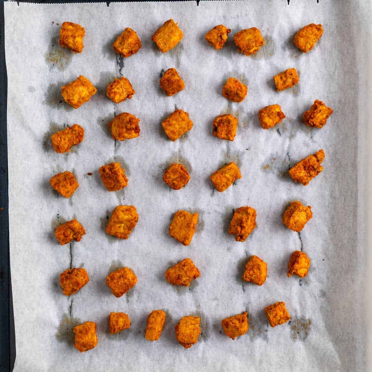 Crispy baked tofu on a lined baking sheet