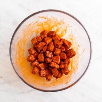 Crispy tofu tossed with buffalo sauce in a bowl
