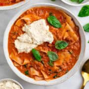 Vegan lasagna soup in a bowl with vegan ricotta and basil on top