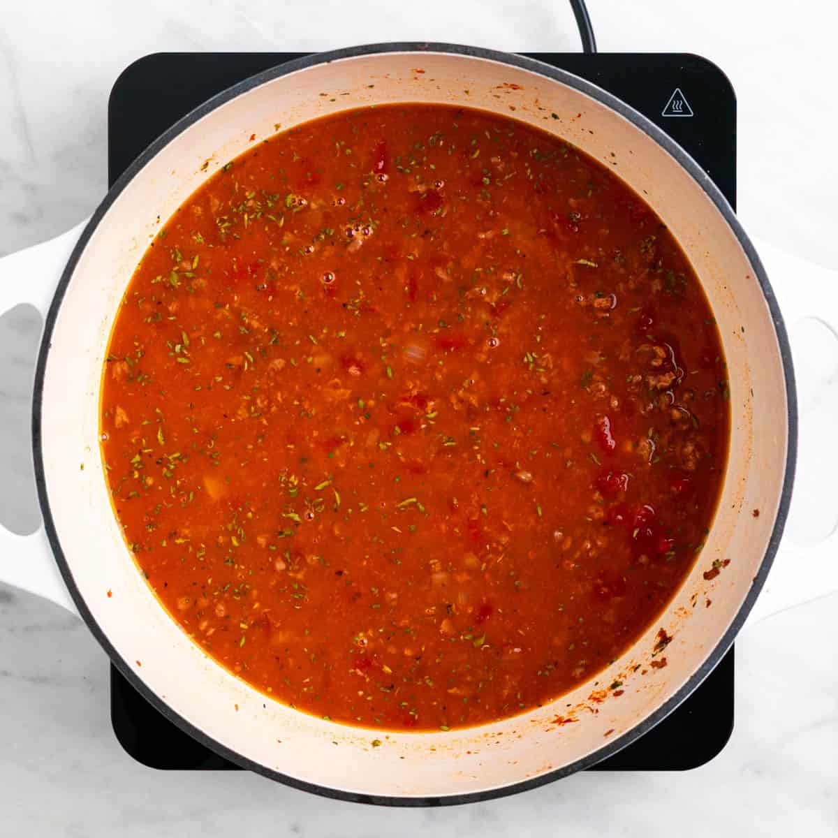 Tomatoes, vegetable broth, and seasonings added to the pot