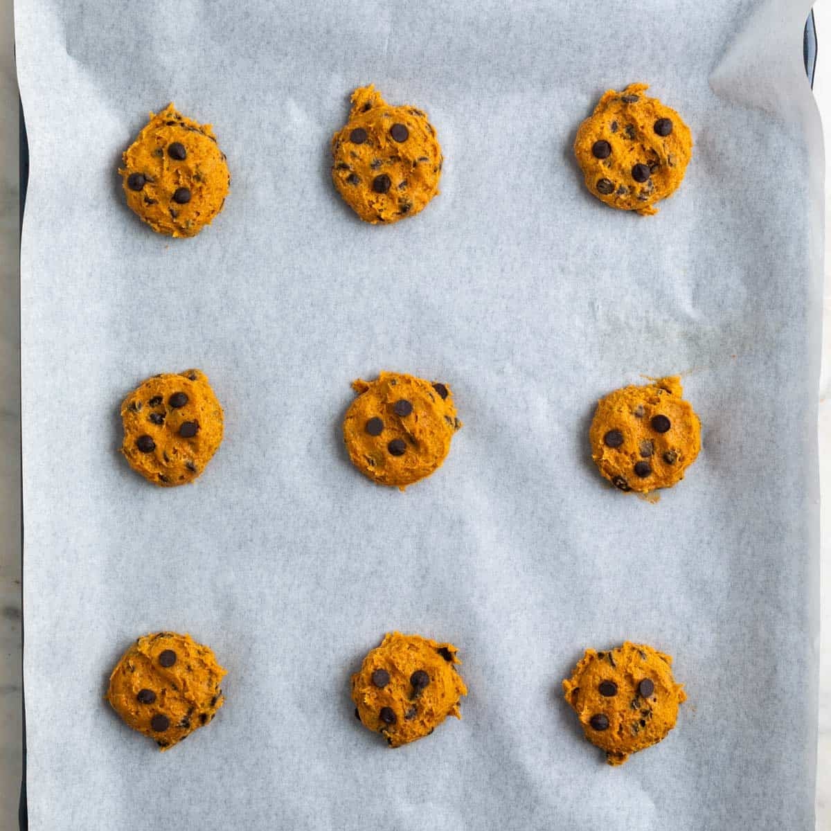 Pumpkin cookie dough portions on lined baking sheets