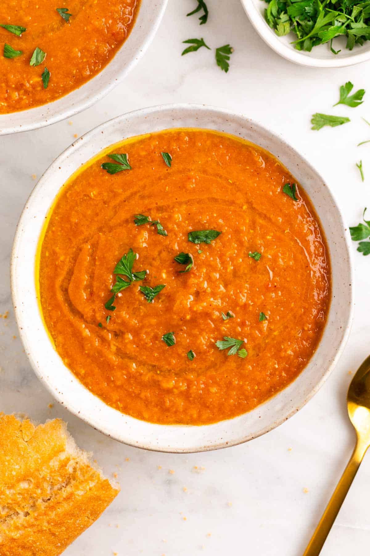 Two bowls of red lentil soup with parsley and olive oil