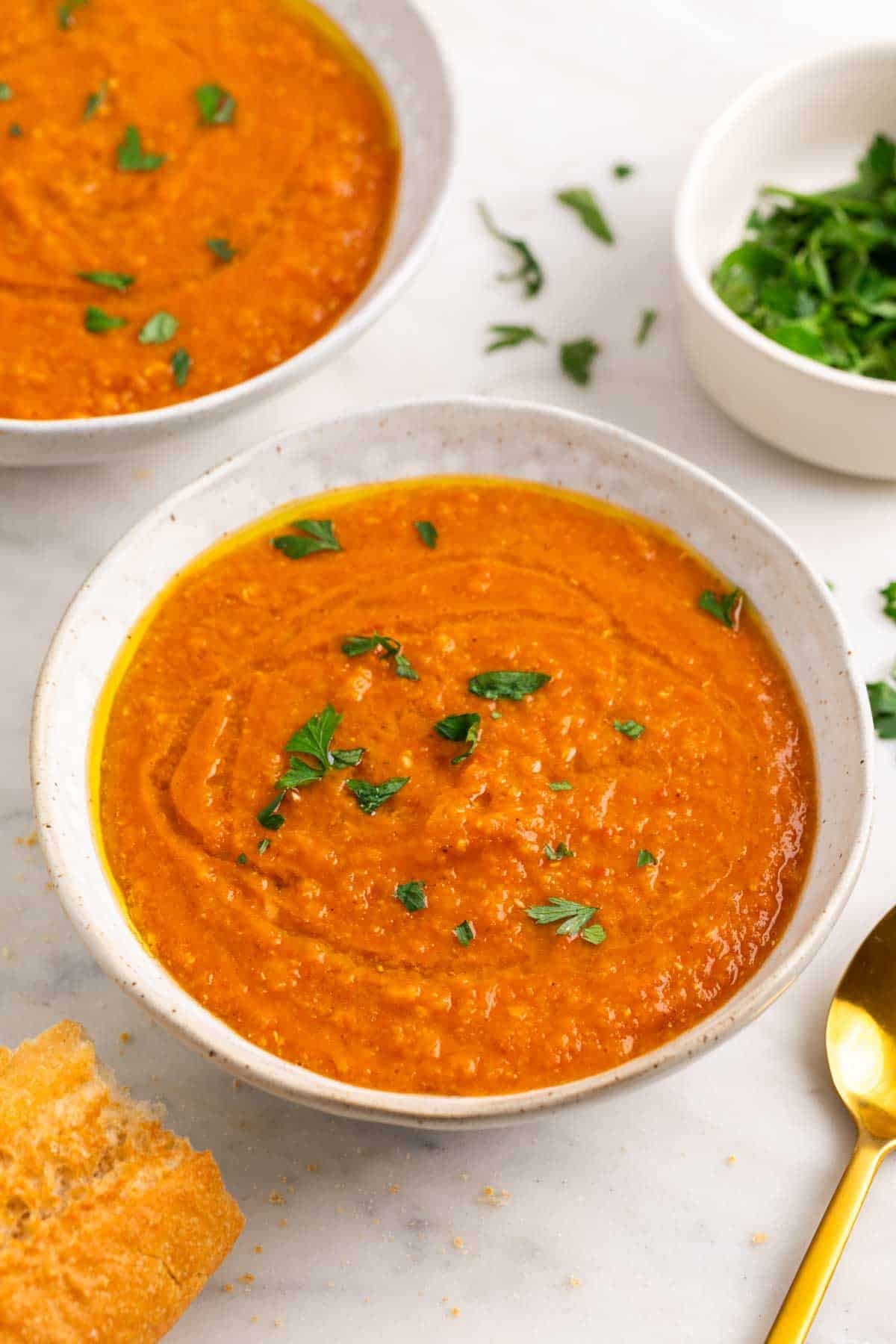Creamy red lentil soup served with bread and parsley