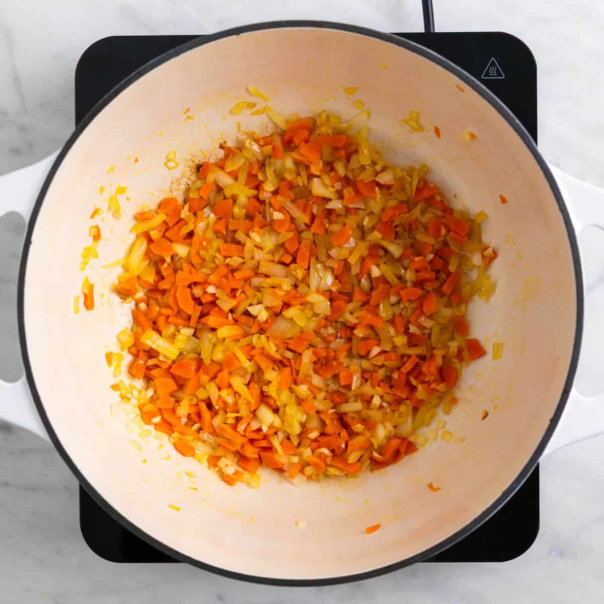 Garlic, onion, and carrots cooking in a pot