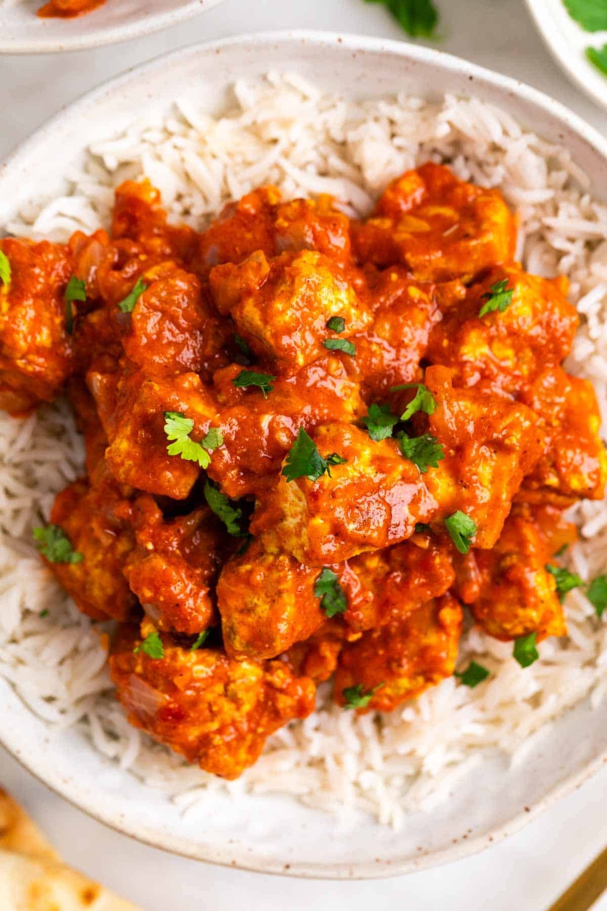 Creamy tofu tikka masala over rice topped with chopped parsley