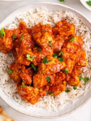 Tofu tikka masala over fluffy basmati rice with pita bread on the side