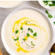 Vegan cauliflower soup with bread, fresh parsley, and a spoon on the side