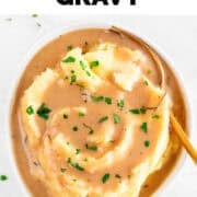 Bowl of vegan mashed potatoes covered in homemade gravy and garnished with chopped parsley