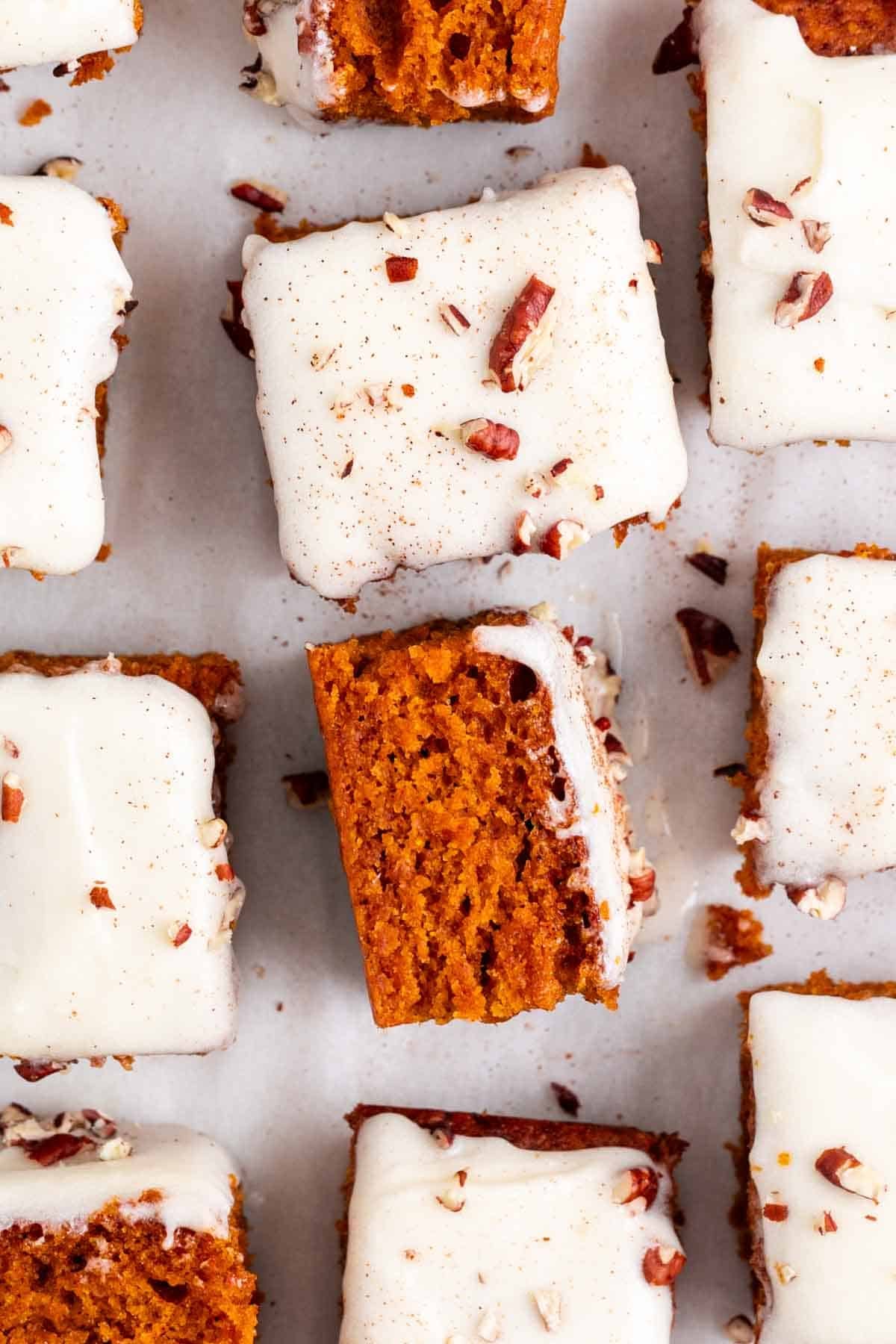 Sliced vegan pumpkin bars with cream cheese frosting, pecans, and cinnamon