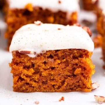 Pumpkin bars cut into squares and topped with chopped pecans and cinnamon