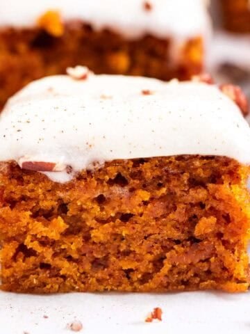 Pumpkin bars cut into squares and topped with chopped pecans and cinnamon